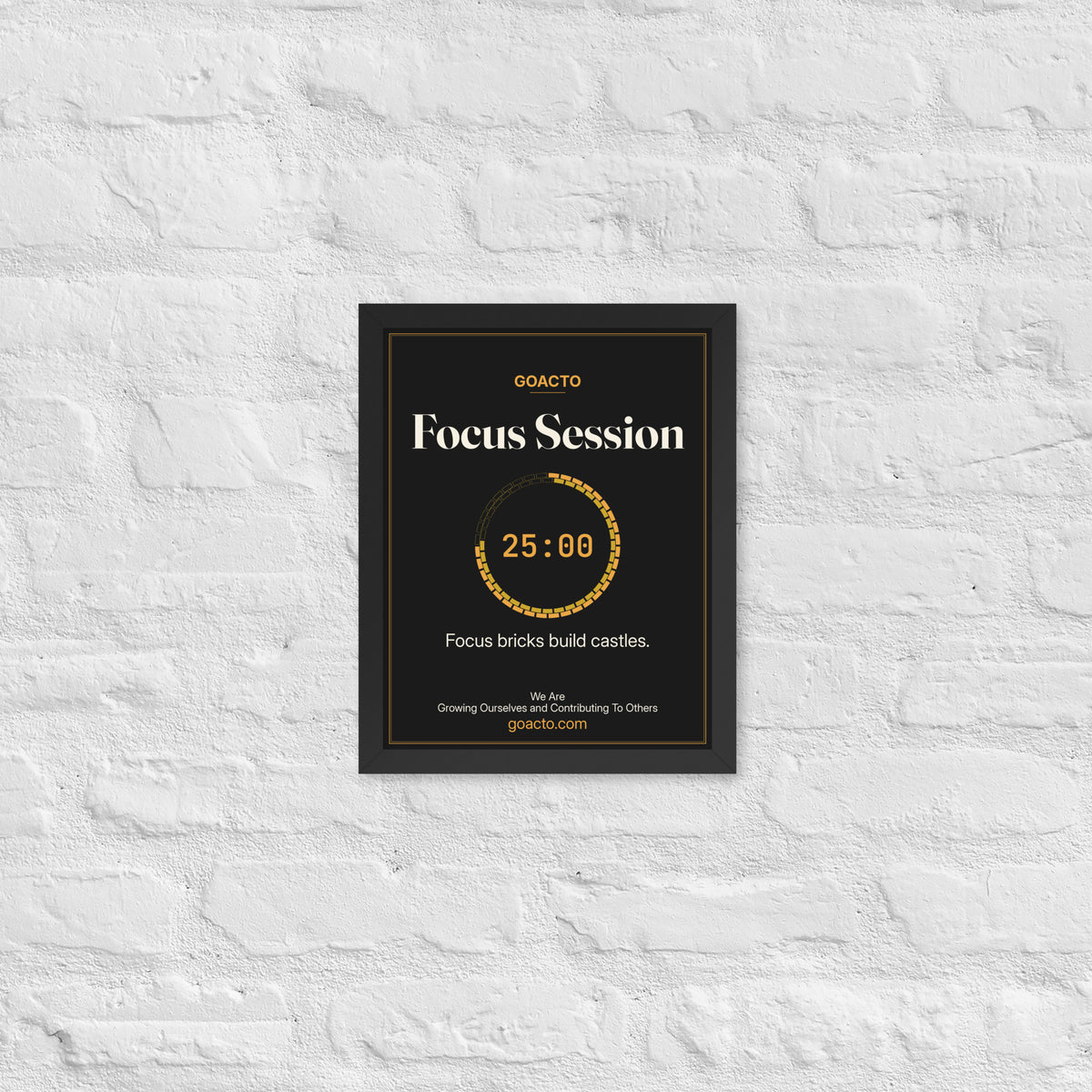 Focus Session Framed Print, Brick Ring design, 11x14 in a black frame on a white brick wall: ring of amber bricks around a 25:00 timer, on charcoal, the line 'Focus bricks build castles.' and 'We Are / Growing Ourselves and Contributing To Others' above goacto.com