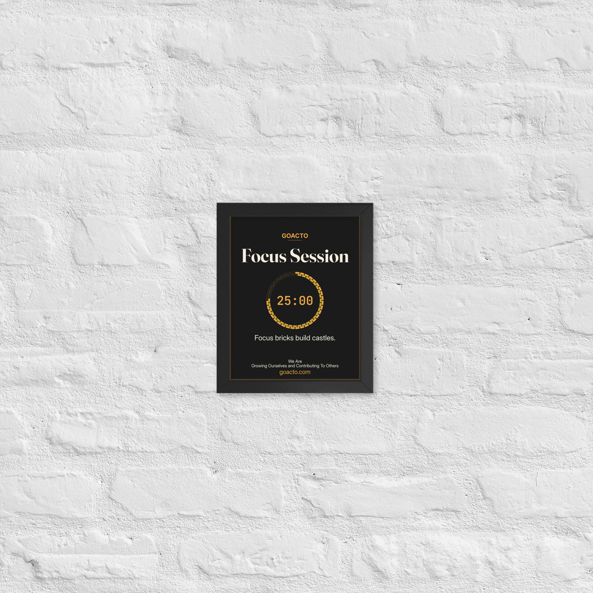Focus Session Framed Print, Brick Ring design, 8x10 in a black frame on a white brick wall: ring of amber bricks around a 25:00 timer, on charcoal, the line 'Focus bricks build castles.' and 'We Are / Growing Ourselves and Contributing To Others' above goacto.com