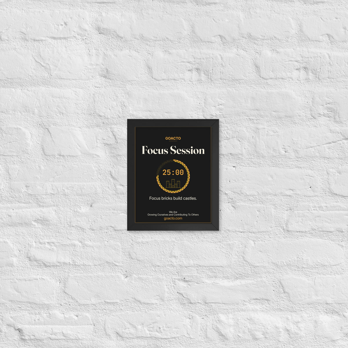 Focus Session Framed Print, Castle Ring design, 8x10 in a black frame on a white brick wall: ring of amber bricks around a 25:00 timer with a small line-drawn castle inside, on charcoal, the line 'Focus bricks build castles.' and 'We Are / Growing Ourselves and Contributing To Others' above goacto.com