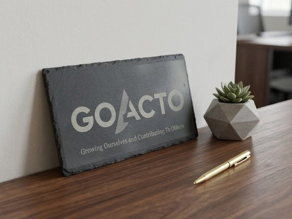 GOACTO slate on a desk with a pen and plant