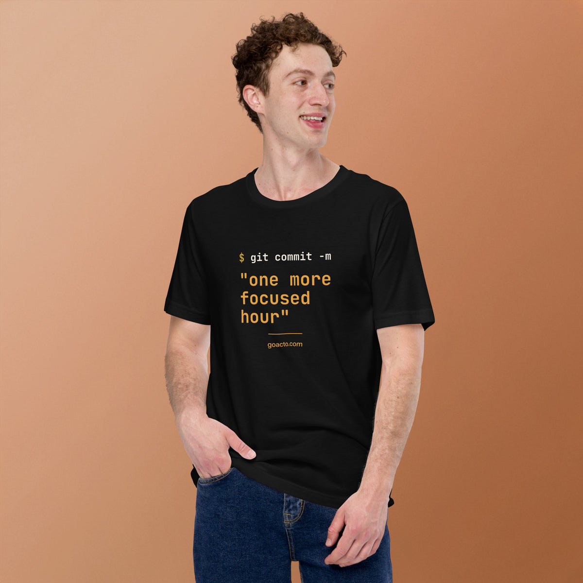 git commit Tee, black, worn by a model against a warm tan background, showing the git commit print on the chest